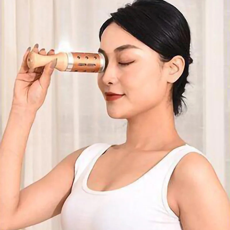 A person is using a moxa stick to perform a facial massage on their own eye area.