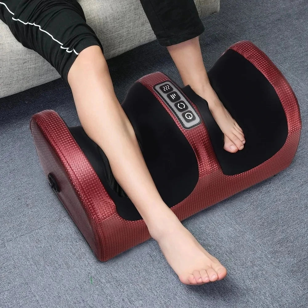 A person using a red and black heated shiatsu foot massager, placed on the floor, with the massager's control panel visible.